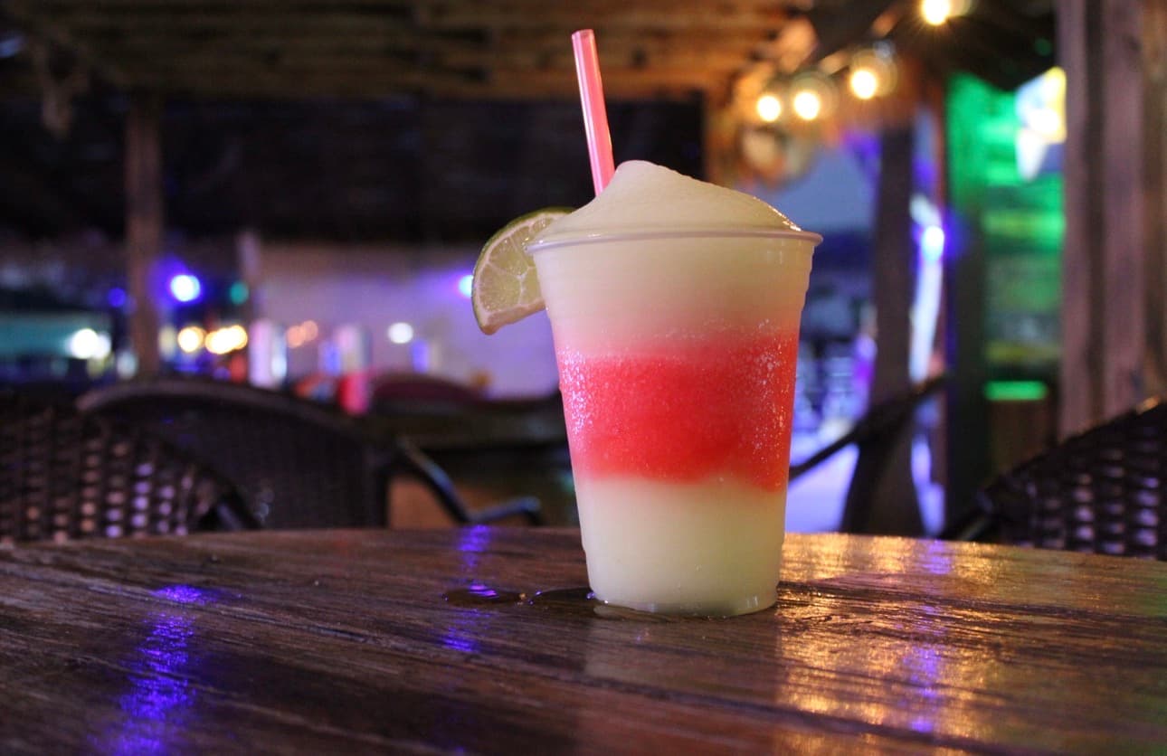 A layered frozen margarita garnished with lime, at Bron's Backyard bar at night